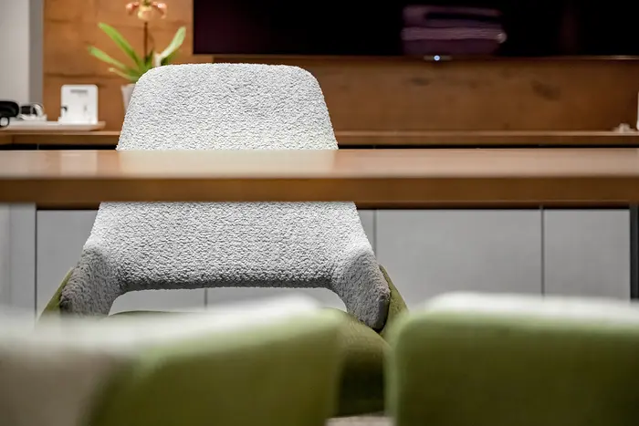 Ein moderner Stuhl mit einem schwarz-weiß gemusterten Bezug vor einem Holztisch und Schränken.