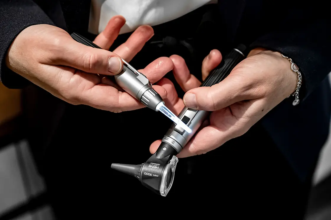 Eine Person hält ein medizinisches Otoskop-Gerät in der Hand.