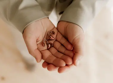 Eine Person faltet ihre Hände auf, in denen sie zwei Hörgeräte hält.