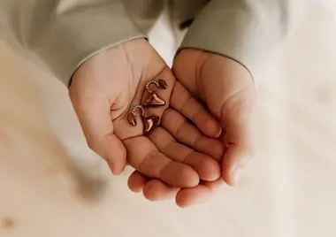 Eine Person faltet ihre Hände auf, in denen sie zwei Hörgeräte hält.