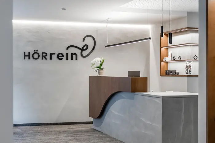 Rezeption der HÖRrein GmbH mit ihrem schwarzen Logo an einer weißen Wand.