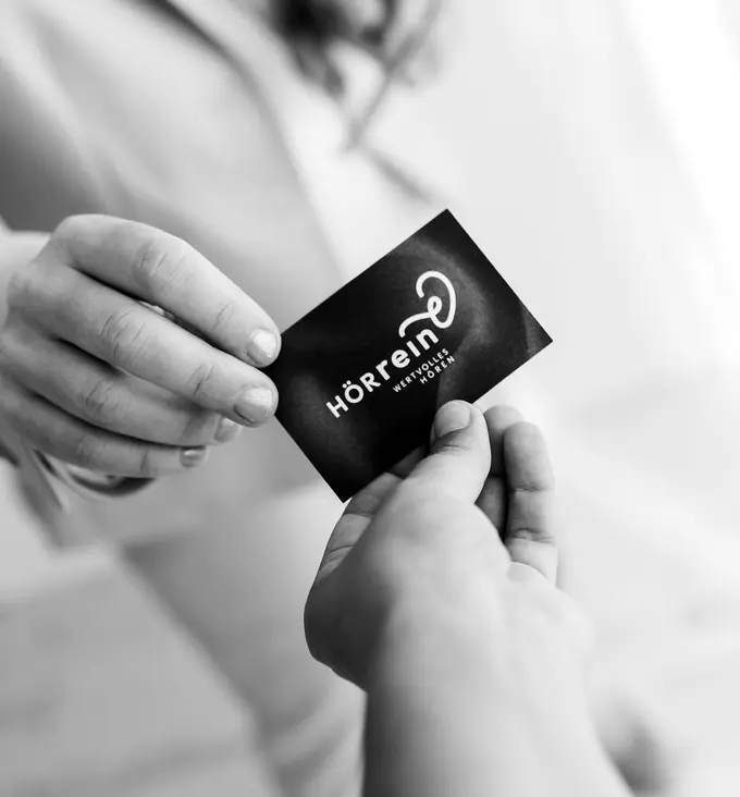 Schwarz-Weiß Foto von der Geschäftsführerin des Unternehmens, wie sie ihre Visitenkarte einer anderen Person übergibt.