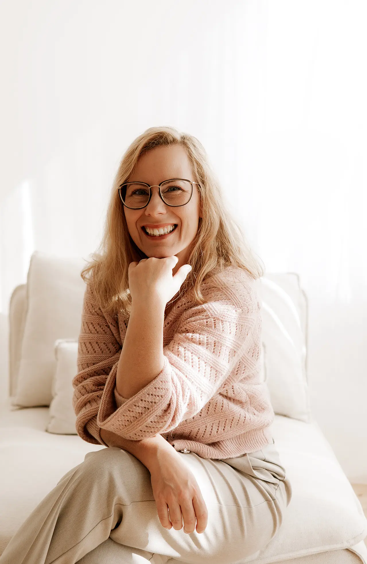 Die Geschäftsführerin sitzt auf einer Couch und lächelt in die Kamera.