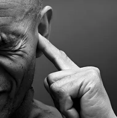 Schwarz-Weiß Foto einer Person, dessen Gesicht nur zur Hälfte zu sehen ist und die sich die Ohren zuhält.